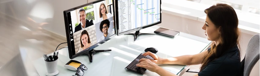 Human resource professional at a desktop on a teleconference with colleagues on the computer screen